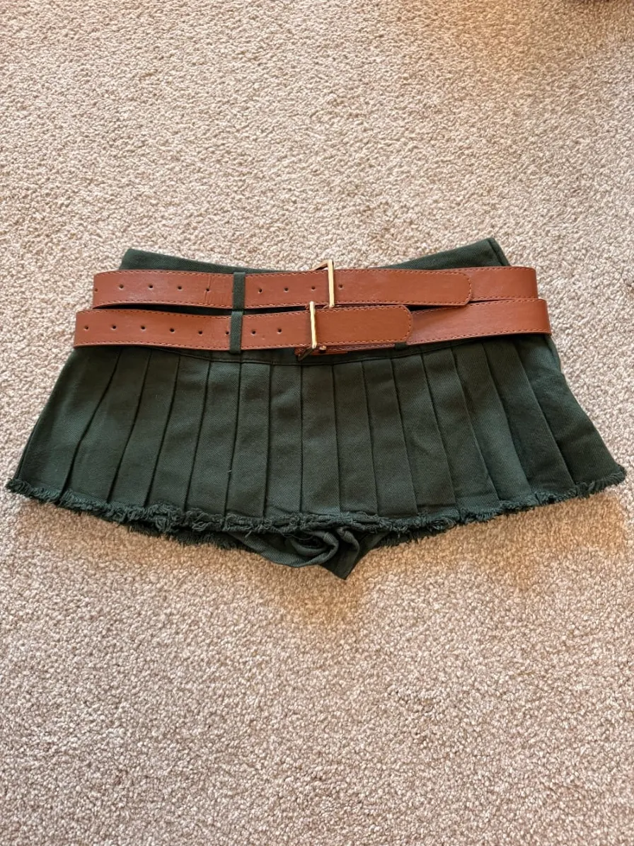 A quick phone snap of an olive pleated mini-skirt laid flat on the carpet, before Vintsnap